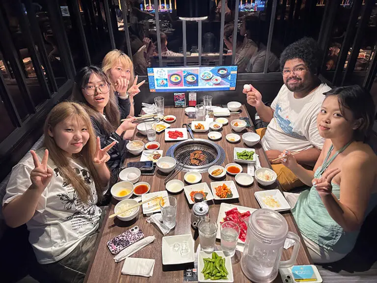 students sitting at dinner table smiling at camera